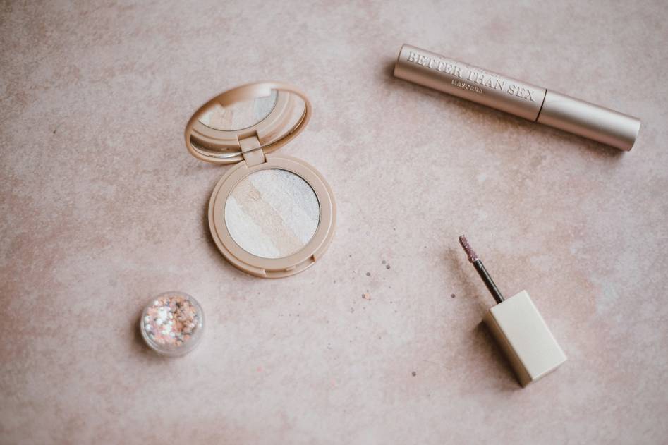 Founder writing notes beside array of clean beauty makeup on wooden table